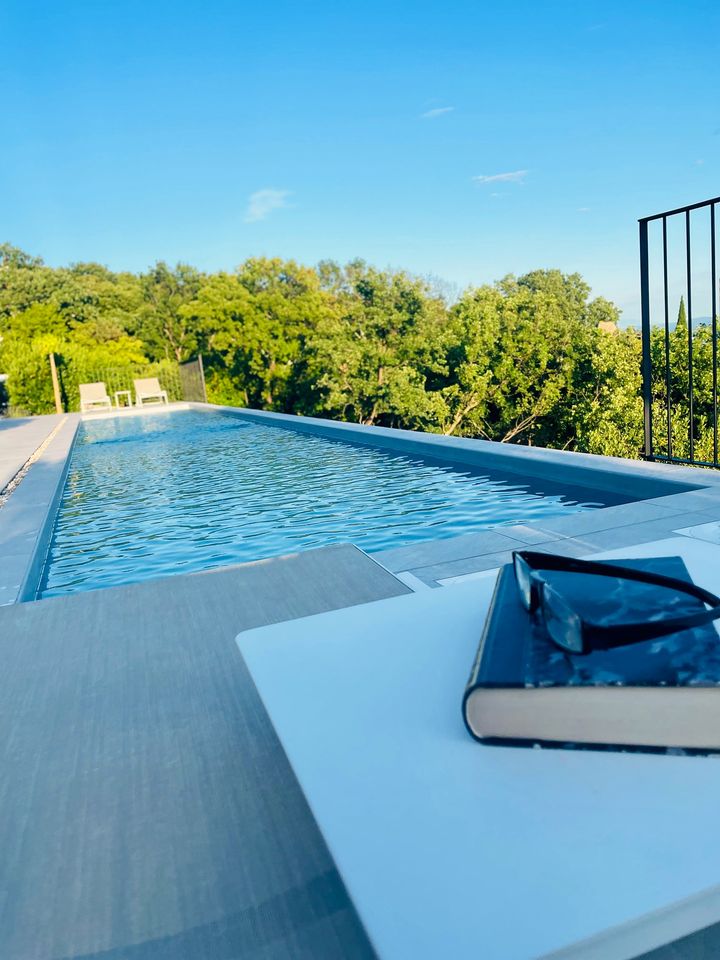 book and sunglasses on lounger by pool