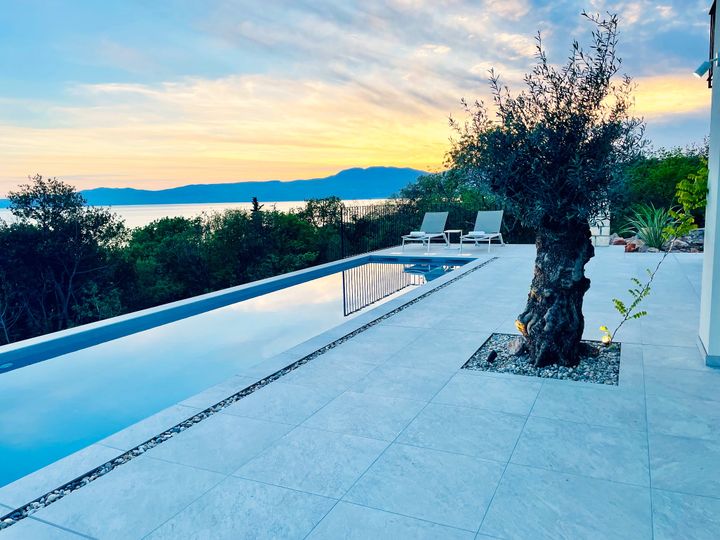 infinity pool and olive tree at golden sunset