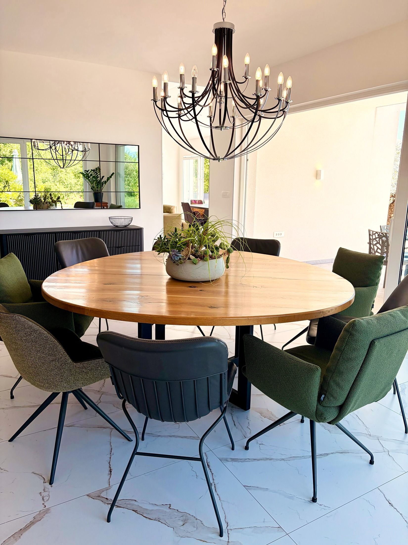 round oak table under chandelier, marble floor