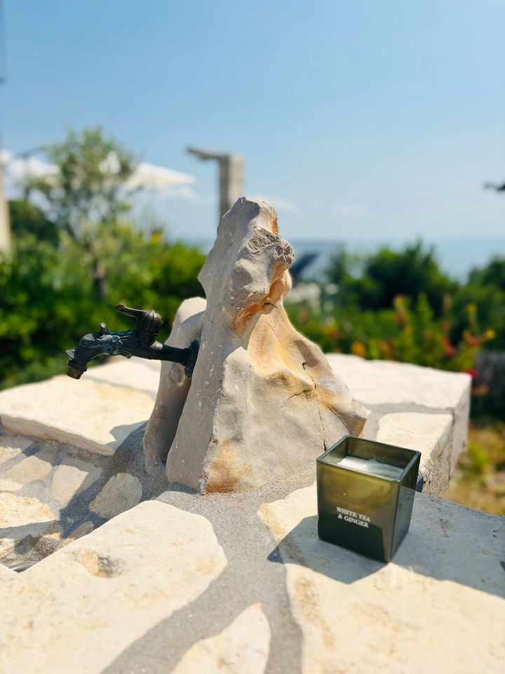 stone fountain tap and a candle on a dry-stone wall above the sea