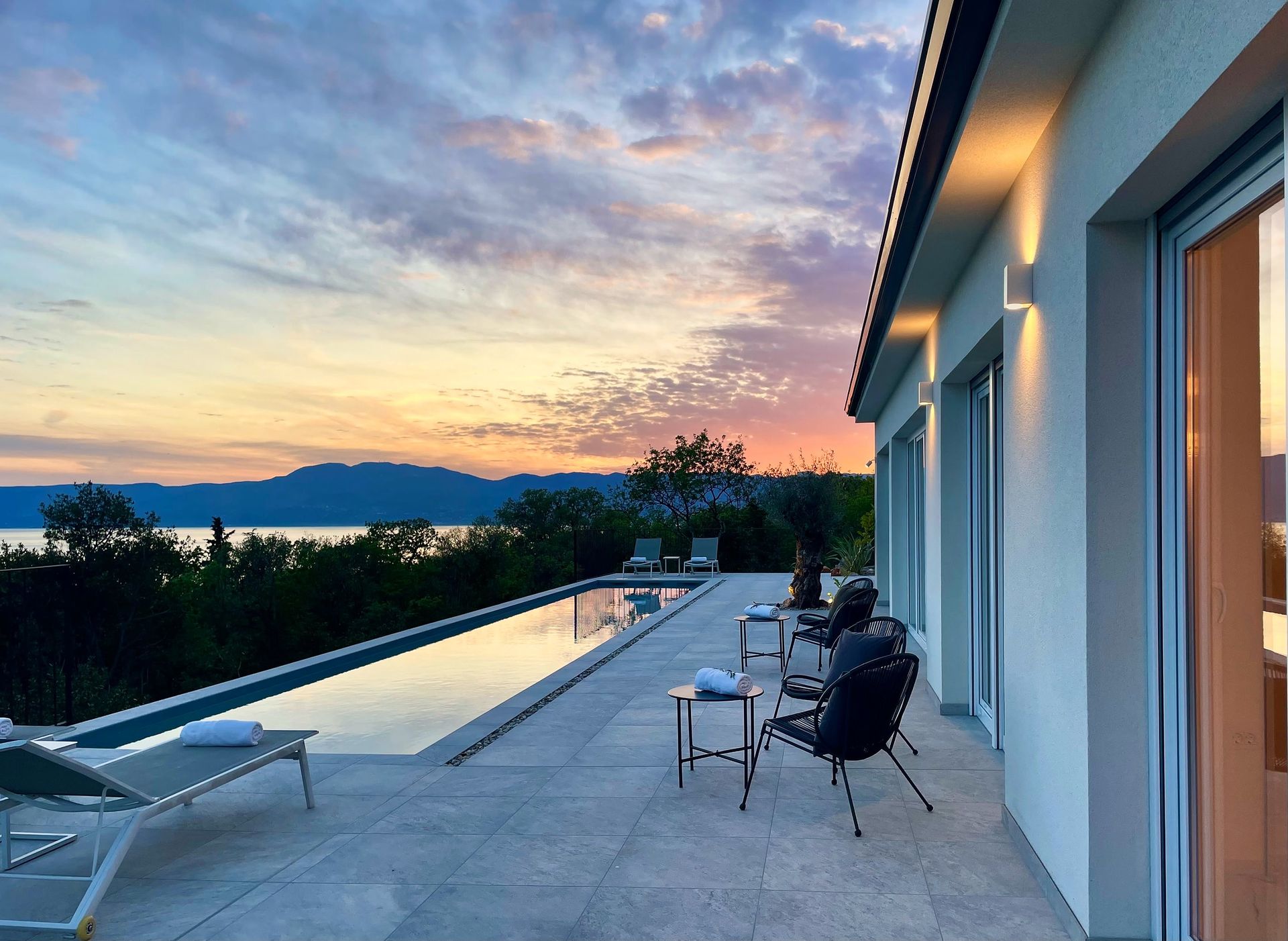 sunset pool terrace with sea and lit sconces