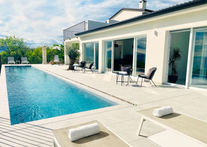 villa and pool terrace with loungers, cloudy sky