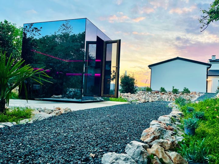 mirrored sauna cube reflecting pastel sunset