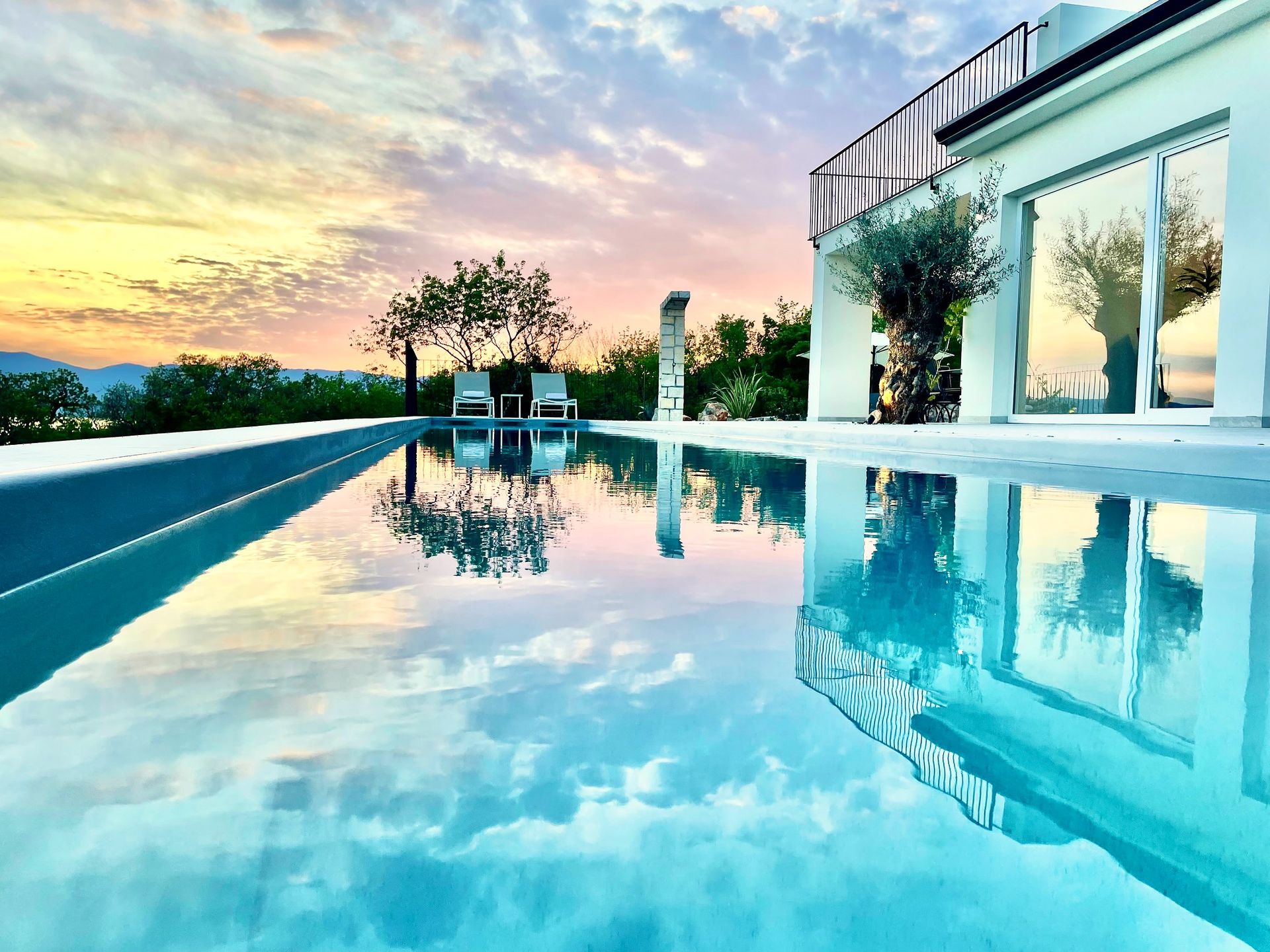 infinity pool mirrors pink dawn sky over Adriatic